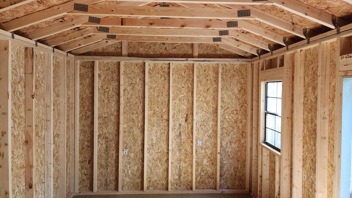 Interior wall of the building showing roof trusses and sheathing.